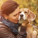 Woman sadly hugs her dog outside after learning of cancer diagnosis.