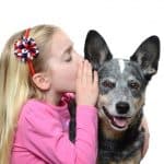 Girl whispering into dog's ear